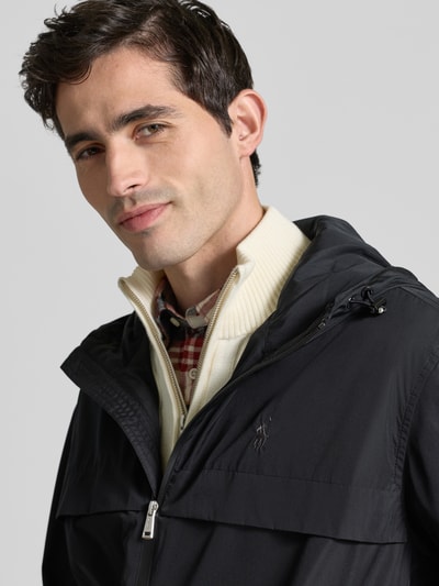 Männermodel trägt Regular Fit Regenjacke mit Logo-Stitching von Polo Ralph Lauren in Optik: Unifarben, Nahaufnahme Oberkörper. Passform: Regular-Fit, Kapuze mit Tunnelzug, Zweiwege-Reißverschluss, Langarm mit elastischem Ärmelabschluss, Rumpfabschluss mit Tunnelzug, seitliche Eingrifftaschen.