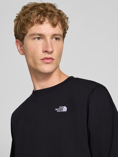 Männermodel trägt schwarzes Regular Fit Sweatshirt Modell "EVOLUTION" von The North Face, Rundhalsausschnitt, Logo-Stitching, Nahaufnahme Oberkörper. Baumwoll-Mix, elastische Abschlüsse.
