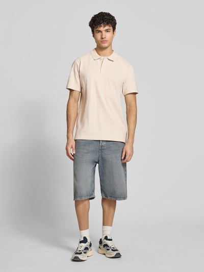 Männermodel trägt Regular Fit Poloshirt mit Logo von G-Star Raw in Beige, Reine Baumwolle, Knopfleiste, Rückenlänge 74 cm, Ganzkörperansicht von vorne.