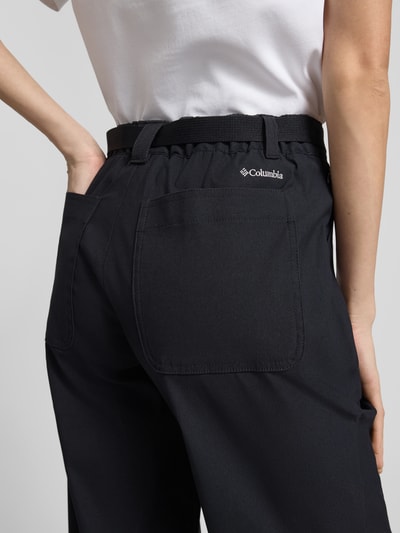 Männermodel trägt Hose mit Gürtel Modell 'BREA FALLS' von COLUMBIA, materiał z domieszką stretchu, krój regular fit, pasek, kieszenie, logo, kolor czarny, Szerokość w rozmiarze S: 35 cm, długość wewnętrzna nogawki: 76 cm, zbliżenie tylnej części.