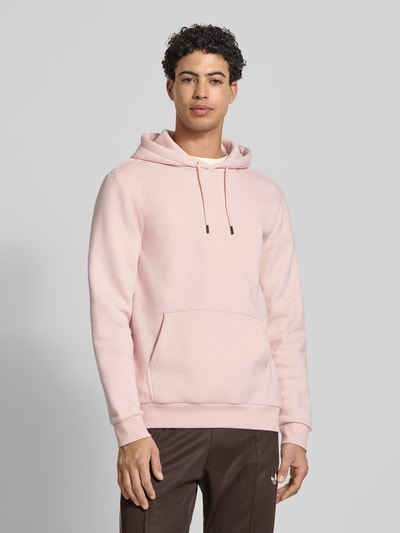 Männermodel trägt Regular Fit Hoodie aus Baumwoll-Mix Modell 'CERES' von Only & Sons in Rosa mit Kängurutasche, Ganzkörperansicht von vorne.