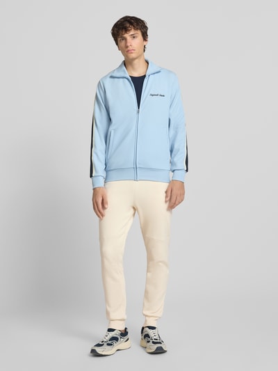 Männermodel trägt Regular Fit Sweatpants mit Label-Applikation von Balr., cremefarben, Baumwoll-Mix, Ganzkörperansicht von vorne.
