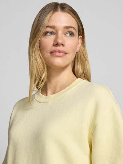 Frauenmodel trägt Sweatshirt mit 1/2-Arm und Rundhalsausschnitt von Rich & Royal, Bio-Baumwoll-Mix mit Stretch-Anteil, Loose-Fit, überschnittene Schultern, seitliche Schlitze, pastellgelb, glatte Textur, Nahaufnahme Oberkörper.