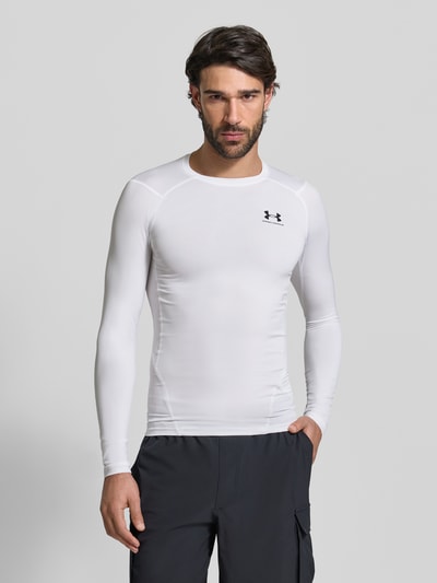 Männermodel trägt Slim Fit Longsleeve mit Logo-Print van Under Armour, wit, elastisch materiaal, ronde hals, heren, vooraanzicht bovenlichaam.