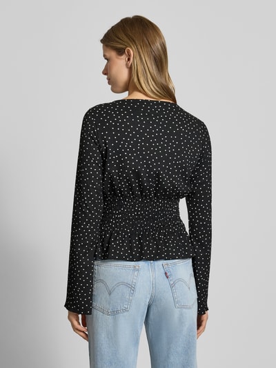 Frauenmodel trägt Longsleeve mit Rundhalsausschnitt von Gina Tricot im Material-Mix mit Stretch-Anteil, Taillierter Schnitt, Smok-Details, Rückenlänge 49 cm, schwarze Grundfarbe mit weißen Punkten, Ganzkörperansicht Rückansicht.