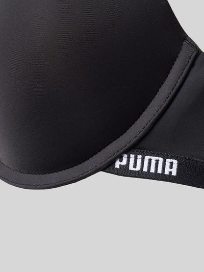 Produktfoto, Push-up-BH mit verstellbaren Trägern von PUMA aus Material-Mix mit Stretch-Anteil, körpernahe Passform, Hakenverschluss, schwarze glatte Oberfläche, weiße PUMA-Schrift auf elastischem Bund.
