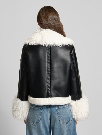 Vrouwenmodel draagt Regular Fit kunstleren jas met dubbele rij knopen model 'SPORTS D' van Marc Cain, zwarte en witte kleuren, dames kunstleren jas, Ganzkörperansicht Rückansicht.
