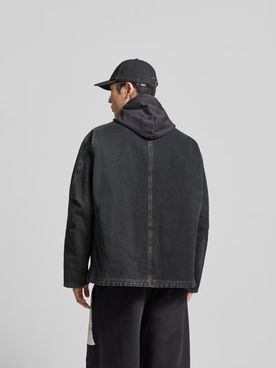 Männermodel trägt Jacke in Denim-Optik mit Umlegekragen von MM6 Maison Margiela aus reiner Baumwolle in Dunkelgrau, Ganzkörperansicht Rückansicht.