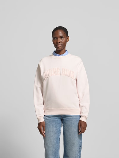 Frauenmodel trägt Regular Fit Sweatshirt mit Logo-Detail von Anine Bing aus reiner Baumwolle in zartem Rosé, Rundhalsausschnitt, elastische Abschlüsse, Rückenlänge bei Größe S: 65 cm, Ganzkörperansicht von vorne.