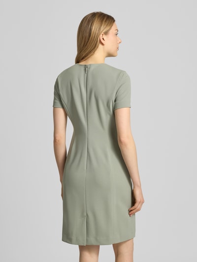 Modelka nosi Knielanges Etuikleid mit Rundhalsausschnitt von Calvin Klein Womenswear, materiał z domieszką stretchu, prosty krój, długość do kolan, kolor jasnoszary, gładka tekstura; widok całej sylwetki z tyłu. Szerokość w rozmiarze S: 43 cm, długość tyłu w rozmiarze S: 92 cm, długość rękawa w rozmiarze S: 19 cm.