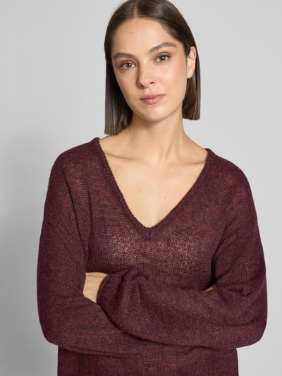 Modelka nosi Relaxed Fit Pullover mit Alpaka-Anteil Model 'Dido' od FREE/QUENT, mieszanka bawełny i wełny z alpaki, półprzezroczysty materiał, dekolt w serek, kolor bordowy, długość tyłu 56 cm, długość rękawów 55 cm, półzbliżenie górnej części ciała.
