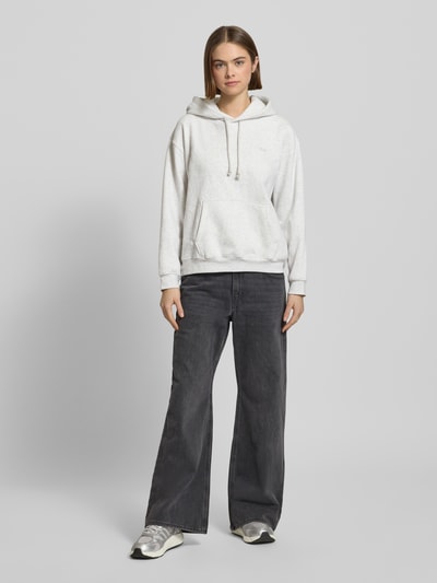 Frauenmodel trägt Hoodie mit Kapuze von Levi's®, Baumwoll-Mix in Hellgrau, lockerer Schnitt, Känguru-Tasche, Ganzkörperansicht von vorne.