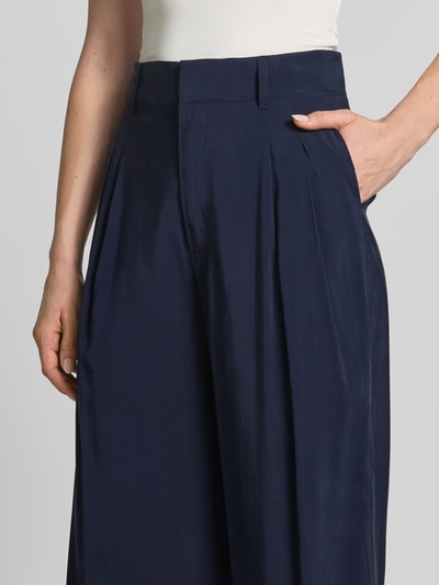 Kobieta nosi Wide Fit Stoffhose aus Viskose-Mix Modell 'Mindy' od My Essential Wardrobe, granatowa, z kieszeniami z tyłu, zapięcie na haczyk i zamek, szerokość w rozmiarze 36: 39 cm, długość wewnętrzna nogawki w rozmiarze 36: 79 cm, zbliżenie na górną część ciała.