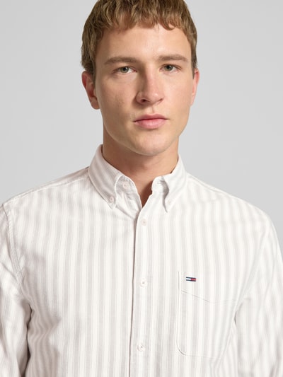 Männermodel trägt Regular Fit Freizeithemd aus reiner Baumwolle von Tommy Jeans, Optik:Allover-Muster, gestreift, Nahaufnahme Oberkörper.