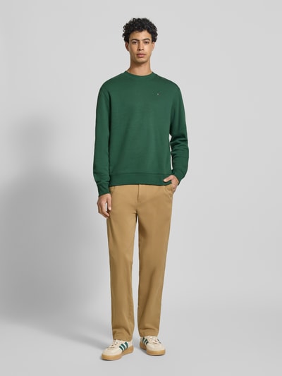 Männermodel trägt Regular Fit Sweatshirt aus Baumwoll-Mix von Tommy Jeans in Optik: Unifarben mit Logo-Stitching, Ganzkörperansicht von vorne.