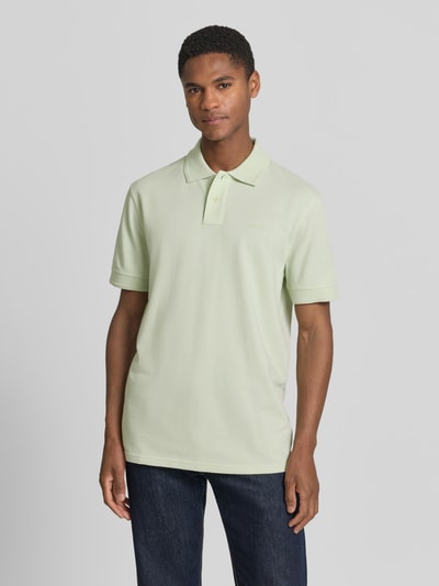 Męski model nosi Regular Fit Poloshirt aus reiner Baumwolle Modell 'PRIME' von BOSS Orange, efekt: jednolity kolor, krój regular fit, naszywka z logo, kołnierzyk polo, dekolt w serek, krótkie zapięcie na guziki, krótki rękaw, prążkowane zakończenie rękawów, wykończenie materiału: pika, bawełna, Ganzkörperansicht von vorne.