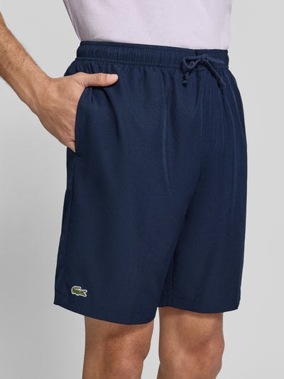 Mannenmodel draagt Relaxed Fit Shorts met logopatch van Lacoste, donkerblauw, gladde textuur, Heren Sportshorts, close-up van de heupen