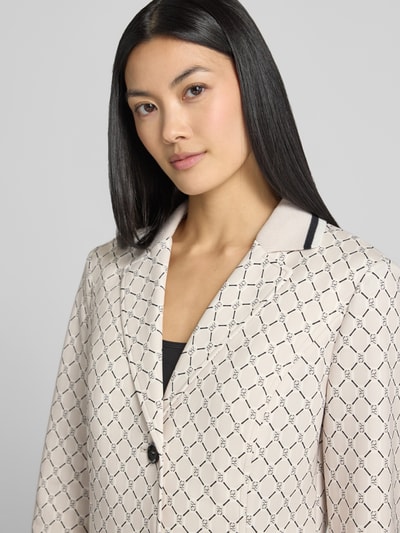 Modelka nosi Slim Fit Blazer mit aufgesetzten Taschen und Knopfverschluss von Marc Cain, mieszanka materiałów z dodatkiem streczu, wzór na całej powierzchni, kołnierz z połami, nakładane kieszenie, zapięcie na guzik, długość tyłu w rozmiarze 36: 58 cm, szerokość w rozmiarze 36: 49 cm, długość rękawów w rozmiarze 36: 60 cm, zbliżenie na górną część ciała.