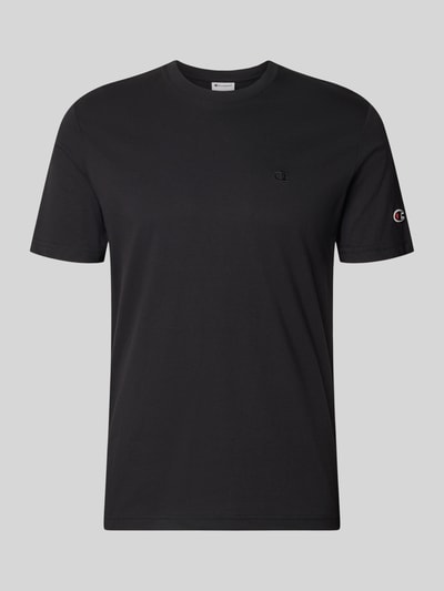 Männermodel trägt T-Shirt mit Label-Stitchings und Rundhalsausschnitt von CHAMPION in Schwarz, Reine Baumwolle, Regular-Fit, Ganzkörperansicht von vorne. Rückenlänge bei Größe M: 66 cm.