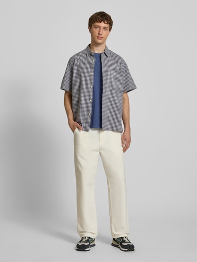 Männermodel trägt Loose Fit Freizeithemd aus reiner Baumwolle Modell 'DAVES' von Only & Sons mit Optik:Allover-Muster kariert, Kentkragen, einreihiger Knopfleiste, Kurzarm, Brusttasche; Material: reine Baumwolle, Ganzkörperansicht von vorne.