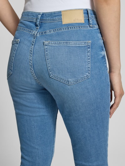 Frauenmodel trägt Slim Fit Caprijeans aus Baumwoll-Mix Modell 'BETSY' von s.Oliver RED LABEL in Denim-Optik, Label-Patch, Nahaufnahme Rückansicht.