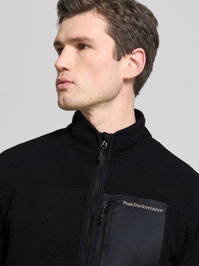 Męski model nosi czarną Fleecejacke mit Zweiwege-Reißverschluss Modell 'NatureRush' von PEAK PERFORMANCE, krój regular fit, widok z przodu, zbliżenie na górną część ciała.