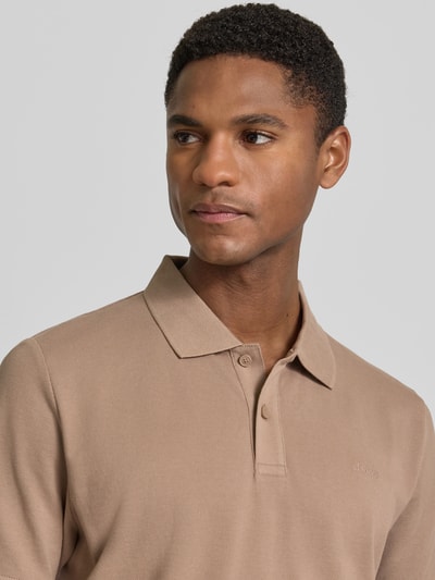 Męski model nosi Regular Fit Poloshirt aus reiner Baumwolle od s.Oliver RED LABEL, efekt: jednolity kolor, pika, wyhaftowane logo, kołnierzyk polo, dekolt w serek, listwa guzikowa, krótki rękaw, prążkowane zakończenie rękawów, wykończenie z rozcięciami po bokach, bawełna, zbliżenie na górną część ciała z przodu.