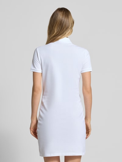 Frauenmodel trägt Slim Fit Polokleid aus Baumwoll-Mix von Lacoste in Weiß, unifarben, kurze Ärmel, Piqué-Struktur, Ganzkörperansicht Rückansicht.
