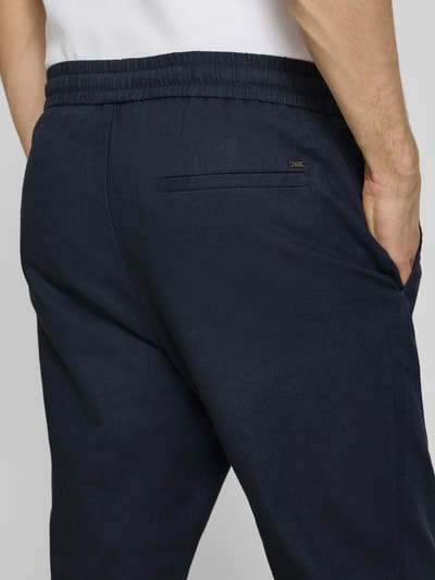Männermodel trägt Tapered Leinenhose aus Baumwoll-Leinen-Mix Modell 'LINUS' von Only & Sons, Melange-Optik Dunkelblau, Detailaufnahme Rückansicht.