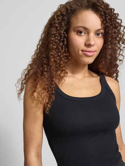 Frauenmodel trägt Slim Fit Top aus Baumwoll-Mix Modell 'ESSENTIAL RIBBED TANK' von Levi's® in Unifarben, Feinripp-Textur, Nahaufnahme Oberkörper.