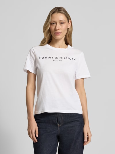 Frauenmodel trägt Regular Fit T-Shirt aus reiner Baumwolle von Tommy Hilfiger in Weiß, unifarben, Logo-Schriftzug, Rundhals, Kurzarm, Jersey-Textur, Nahaufnahme Oberkörper.