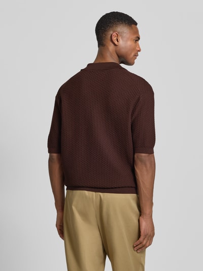 Männermodel trägt Regular Fit Poloshirt aus reiner Baumwolle Modell 'H-Natalo' von BOSS in brauner Flechtoptik, Strukturmuster, kurze Ärmel, Rippabschlüsse, Ganzkörperansicht Rückansicht.