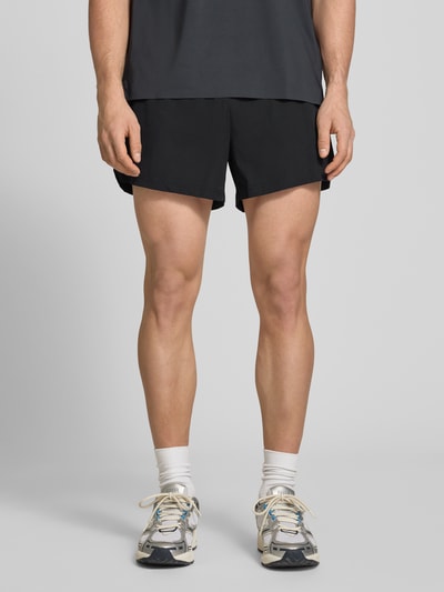 Männermodel trägt schwarze Shorts mit elastischem Bund Modell 'ERUDITO' von Ellesse, Material-Mix mit Stretch-Anteil, Regular-Fit, Ganzkörperansicht von vorne.