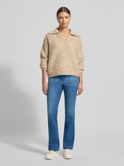 Frauenmodel trägt Flared Fit Jeans mit Flecht-Detail Modell 'Mary' von BRAX im zeitlosen Jeans-Look aus elastischem Baumwoll-Mix, aufgesetzte Gesäßtaschen, mittlere Waschung, Bundweite 39 cm, Innenbeinlänge 80 cm, Ganzkörperansicht von vorne.