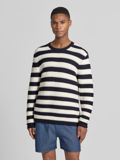 Männermodel trägt Regular Fit Strickpullover aus reiner Baumwolle von Tommy Hilfiger, gestreift, Optik:Allover-Muster, Ganzkörperansicht von vorne.