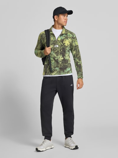 Männermodel trägt Regular fit sweatshirt Model 'NOVELTY' met camouflagemotief van The North Face, heren, elastische boordjes, schipperstrui, ruglengte maat M 71 cm, mouwlengte 69 cm, all-over groene tinten, ganzkörperaanzicht van voren.
