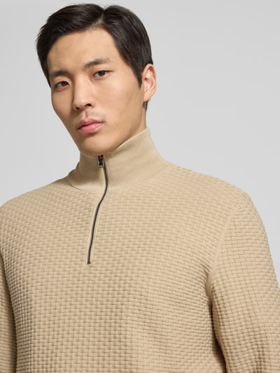 Männermodel trägt Regular Fit Troyer aus reiner Baumwolle Modell 'H-ULICIO' von BOSS in beige Strickoptik, Nahaufnahme Oberkörper.