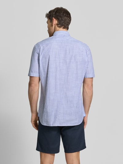 Mężczyznamodel nosi Regular Fit Freizeithemd mit Brusttasche od Christian Berg Men z bawełny, krótki rękaw, kołnierzyk typu button down, granatowe i białe paski, brustasza, listwa guzikowa, długość tyłu 79 cm, szerokość w rozmiarze M 47 cm, długość rękawów 26 cm, widok całej sylwetki z tyłu.