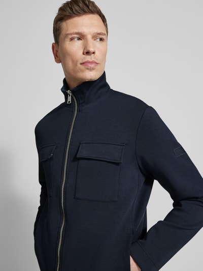 Męski model nosi Regular Fit Sweatjacke aus Baumwoll-Mix od Marc O'Polo, ciemnoniebieska, długi rękaw, kieszenie na piersi, scuba, z przodu, zbliżenie na górną część ciała.