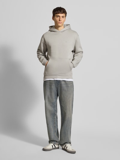 Männermodel trägt Hoodie mit Label-Print von REVIEW in Grau, Baumwoll-Mix, Känguru-Tasche, Gerippte Abschlüsse, Ganzkörperansicht von vorne.
