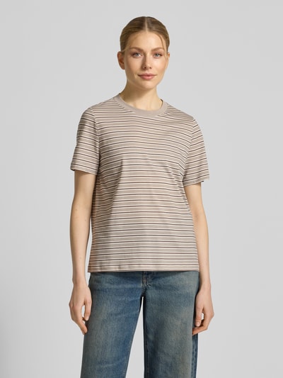 Frauenmodel trägt Regular Fit T-Shirt aus reiner Baumwolle Modell 'PAULINA' von Vero Moda mit Optik:Allover-Muster, gestreift, Rundhals, Kurzarm, Jersey, beige-braune Streifen auf glatter Oberfläche, Ganzkörperansicht von vorne.