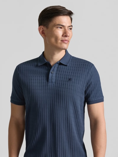 Männermodel trägt Slim Fit Poloshirt mit Logo-Stitching von Lerros in Dunkelblau, Strukturmuster, elastischer Baumwoll-Mix, Nahaufnahme Oberkörper.