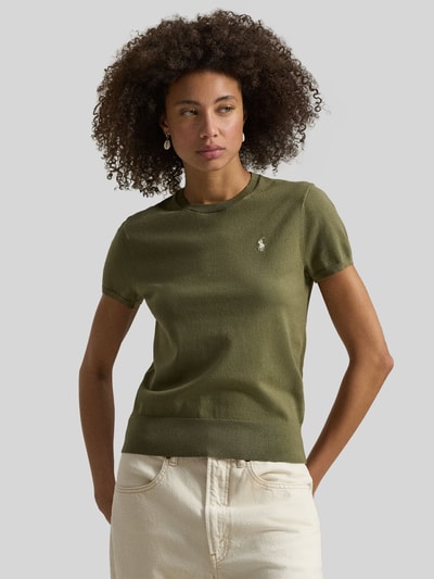 Kobiece model prezentuje Regular Fit Kurzarmpullover mit Logo-Stitching od Polo Ralph Lauren, elastyczna bawełna, dekolt okrągły, krótkie rękawy, oliwkowy kolor, szorstka tekstura, widok całej sylwetki z przodu.