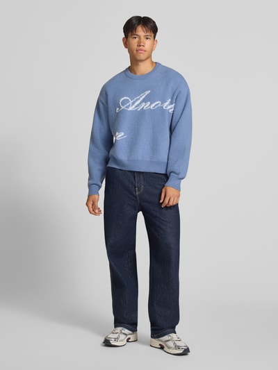 Męski model ma na sobie sweter 'Pullover mit geripptem Rundhalsausschnitt' od ANOTHER COTTON LAB, prosty krój, prążkowany okrągły dekolt, prążkowane wykończenia, długość tyłu w rozmiarze M: 61 cm, długość rękawów w rozmiarze M: 63 cm, odcień niebieski, gładka faktura, całkowity widok z przodu.