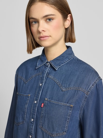 Frauenmodel trägt Hemdbluse in Denim-Optik von Levi's®, Lyocell-Baumwoll-Mix, Knopfleiste, Brusttaschen, Label-Detail, Nahaufnahme Oberkörper.