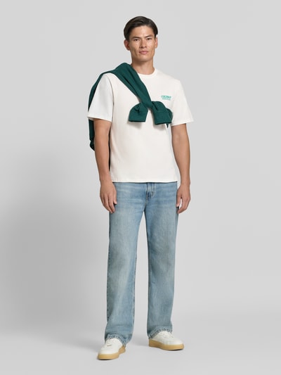 Männermodel trägt Relaxed Fit T-Shirt aus reiner Baumwolle von REVIEW, weiß mit Motiv-Print, gerippte Blende, kurzärmelig, Ganzkörperansicht von vorne.
