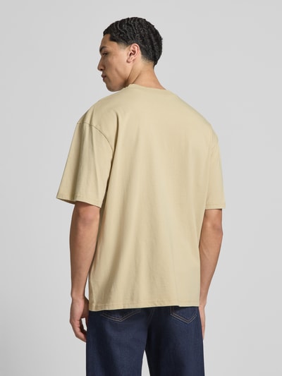 Mannelijk model draagt Oversized Fit T-shirt met logo-stitching van Pegador in beige, puur katoen, ronde hals, ruglengte bij maat M 71 cm, Ganzkörperansicht Rückansicht.