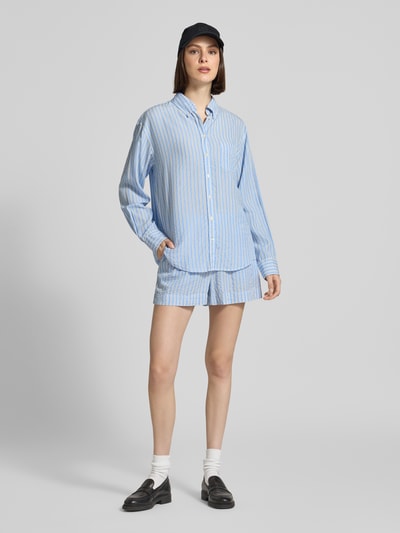 Frauenmodel trägt Relaxed Fit Bluse aus Lyocell mit Button-Down-Kragen von Gant, hellblaue Streifen, Knopfleiste, Brusttasche, Rückenlänge 73 cm, Ärmellänge 59 cm, Ganzkörperansicht von vorne.