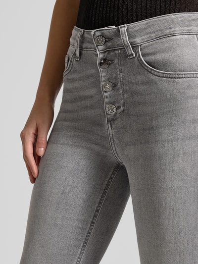 Frauenmodel trägt Jeans mit Knopfleiste Modell 'PRINCESS' von Liu Jo White im Used-Look, Slim-Fit, Baumwoll-Lyocell-Anteil, Nahaufnahme Oberkörper.
