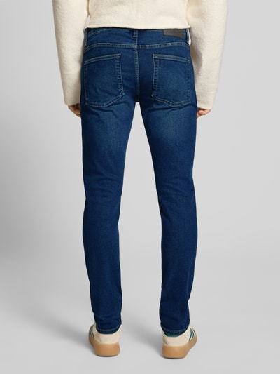 Männermodel trägt Slim Fit Jeans aus Baumwoll-Mix Modell 'LOOM' von Only & Sons in Blau, unifarben, Denimstruktur, Ganzkörperansicht Rückansicht.